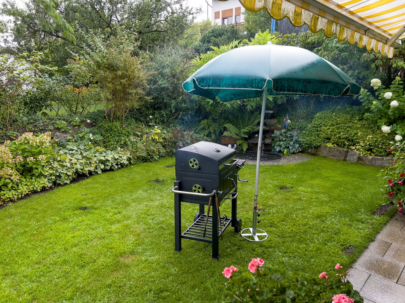 Garten mit Grillplatz und Sonnenschirm bei Regen | Terrassenüberdachung