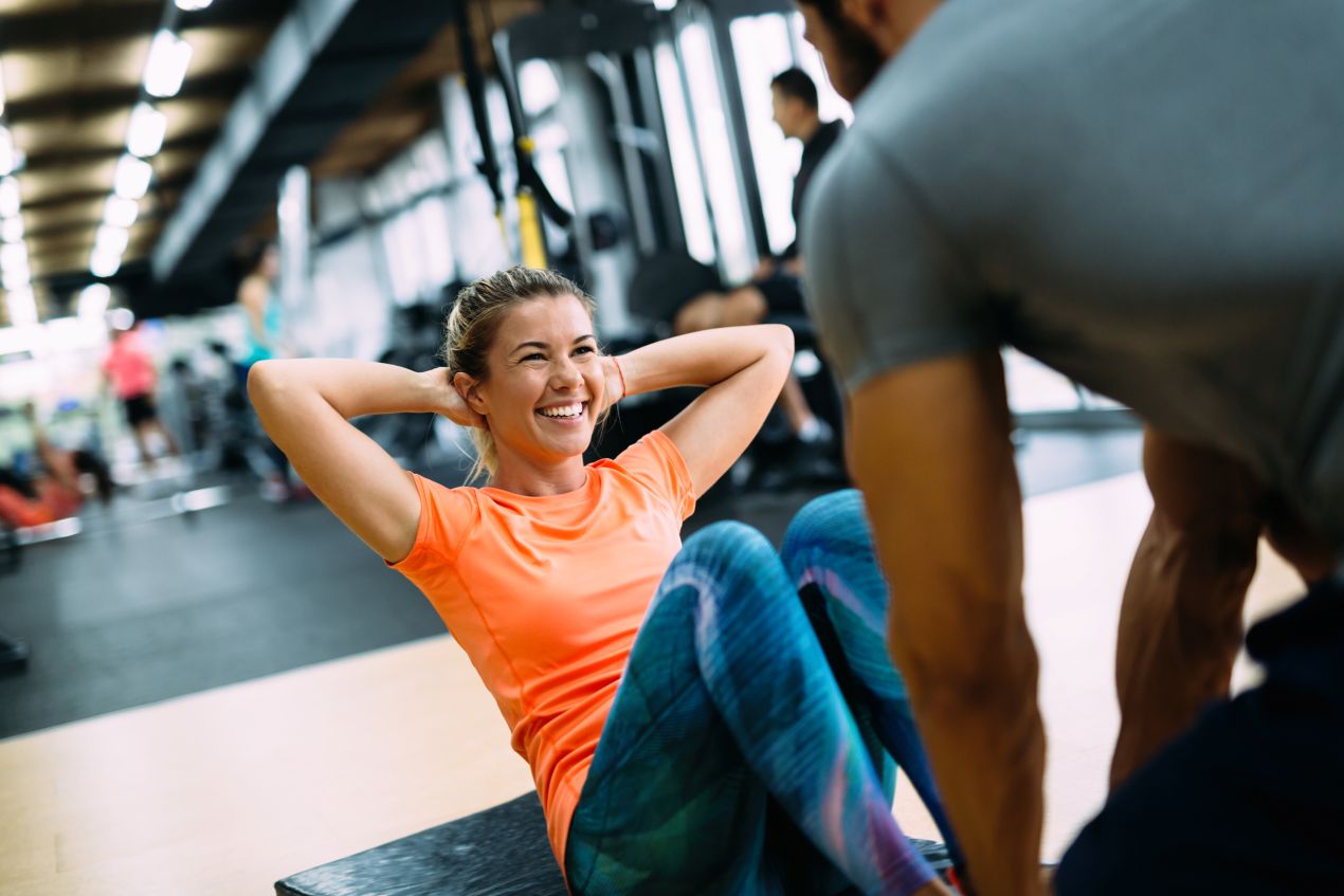 Frau trainiert mit Freude und Motivation im Fitnessstudio unter Anleitung eines personal trainer koeln