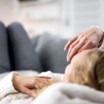 Frau liegt erschöpft auf dem Sofa und erholt sich nach Krankheit – Symbol fuer Ruhe und Heilungszeit mit Unterstuetzung durch den Pflegedienst Bielefeld.